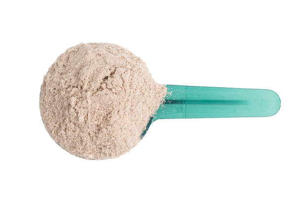 istock Chocolate whey protein powder in a plastic measuring spoon, isolated on white background, top view 1958095131