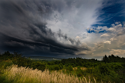 Thunderstorm over meadows with dark sky and big cumulonimbus thundercloud