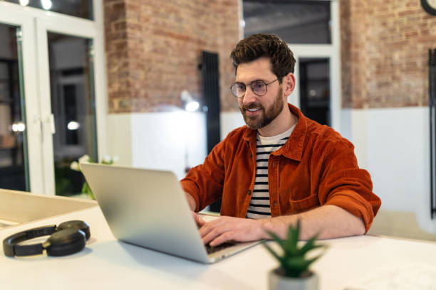istock Young dark-haired man in headphones working on laptop 1958114160