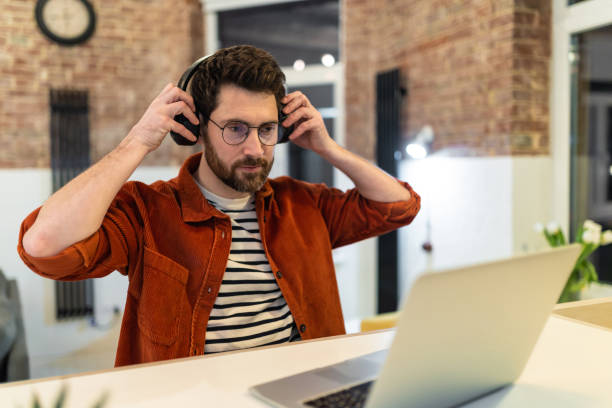 istock Young dark-haired man in headphones working on laptop 1958114167