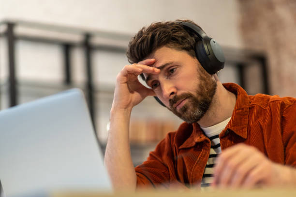 istock Young man sitting at laptop and looking tired 1958114685