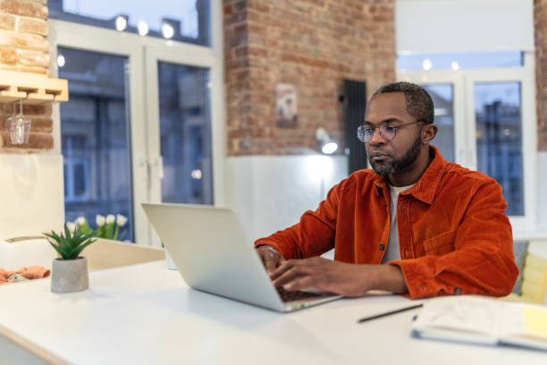 istock Dark-skinned man in red shirt working and looking involved 1958115269