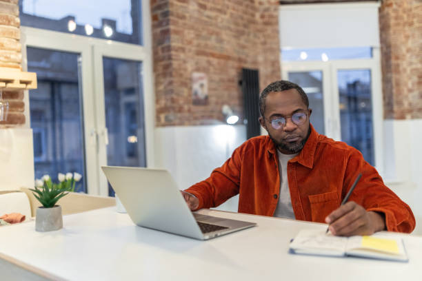 istock Dark-skinned man in red shirt working and looking involved 1958115272