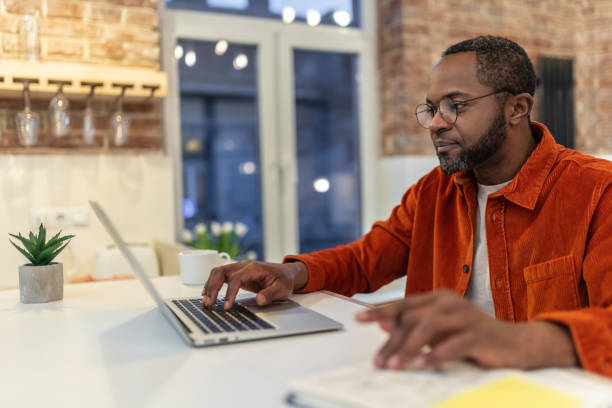 Dark-skinned man in red shirt working and looking involved