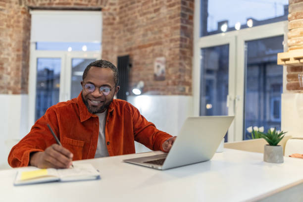 istock Dark-skinned man in red shirt working and looking involved 1958115792