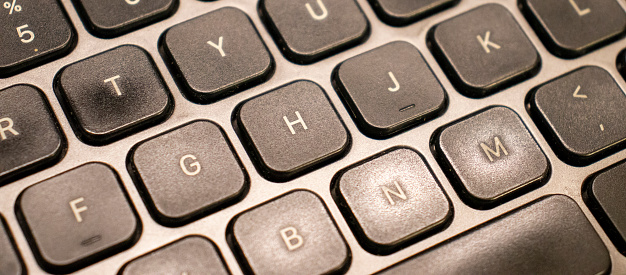 Closeup shot of a black laptop keyboard in ambient light.