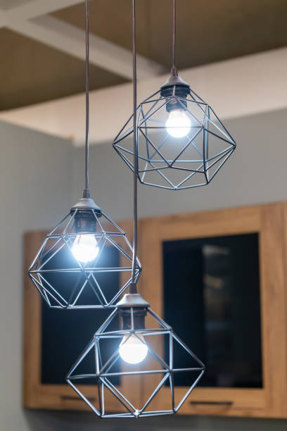 istock Modern wire ceiling lights. Three modern wire lampshades with glowing LED lamps in the interior. 1958138856