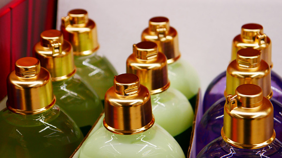 Many colorful bottles of perfume standing in a row close-up