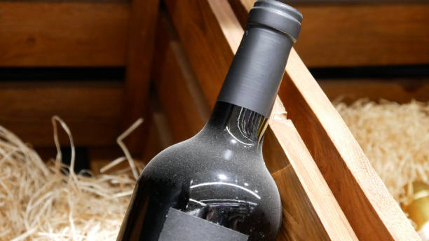 close-up of a dusty bottle of aged wine in a wooden box - dust old cabernet sauvignon grape aging process imagens e fotografias de stock