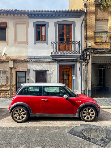 Valencia, Spain - October 26, 2023: Side view of red Mini car parked in the street.  This British automotive brand founded in 1969 is owned by German automotive company BMW since 2000 and produce small compact cars