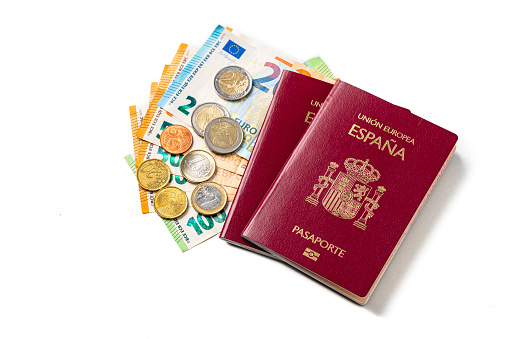 Two Spanish passports and European Union currency isolated on white background. Copy space. High resolution 42Mp studio digital capture taken with Sony A7rII and Sony FE 90mm f2.8 macro G OSS lens