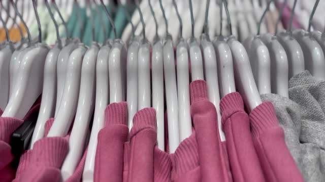 Hanging clothes rack and rail on clothes hangers in fashion clothes shop 4k stock video