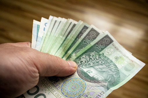 Closeup shot of a hand holding Polish złoty banknote in business setting.
