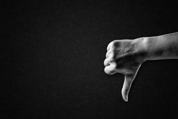Hand Showing Thumb Down Dislike Sign in Black and White on Textured Paper Background, Copy Space