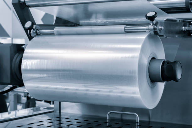 istock Automatic polyethylene plastic bag production machine with lighting effect. Close-up of the roller of the plastic bag production machine in the light blue scene. product packaging concept 1958233612
