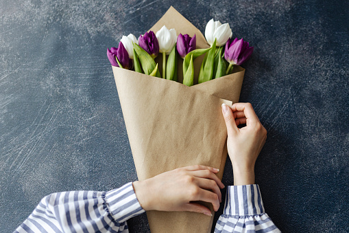 Photo of human hands creating tulip bouquet