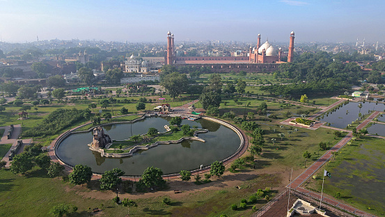 An aerial shot of an artificial lake and a map of the country constructed before the historical Mosque of Lahore.