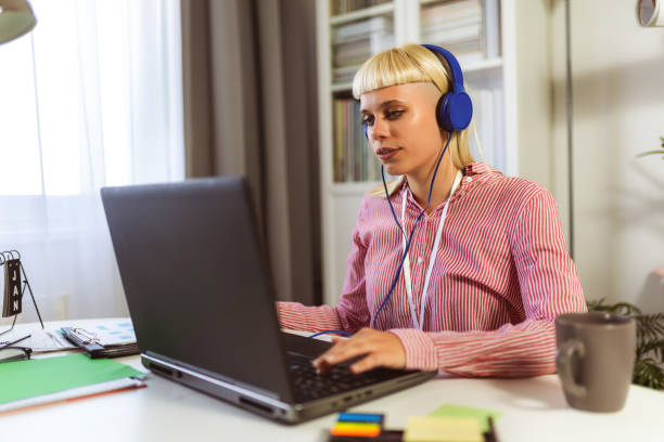 istock Young blonde woman smiling while working on her laptop 1958286875