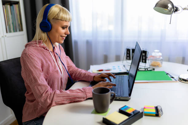 istock Young blonde woman smiling while working on her laptop 1958286883
