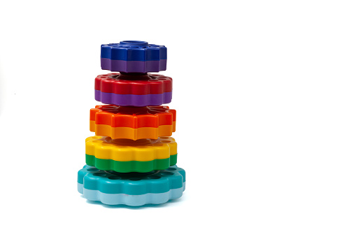 Multicolored plastic round discs for children's pyramid game. Yellow with green, blue with blue, orange and yellow, purple disks with wavy edges for young children to play on a white background. One on one. High quality photo.
