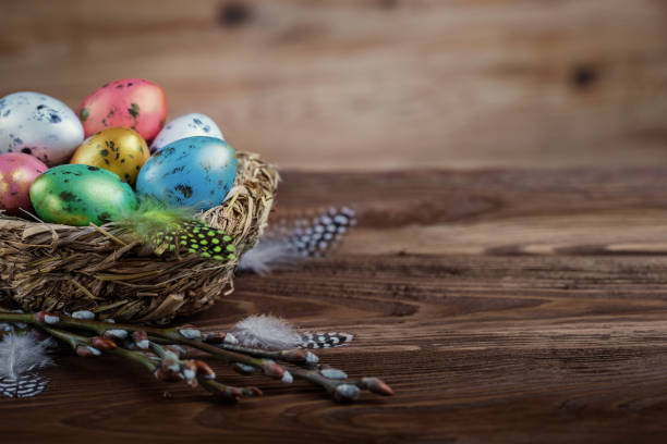 istock Easter composition with painted Easter eggs in a bird's nest on the wooden background. 1958315793