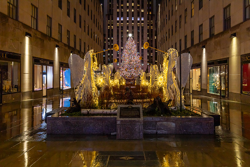 New York, NY, USA - December 11, 2023: Rockefeller Center during Christmas time with the tree lit up and looking through the angels with trumpets.