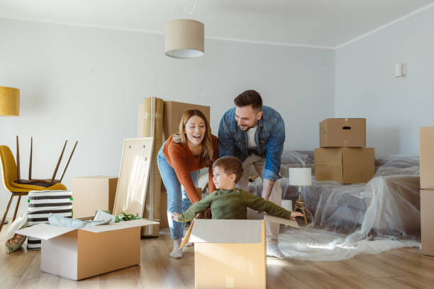 Playful happy family having fun moving into new apartment Happy family with one child having fun in their new home surrounded by boxes moving out stock pictures, royalty-free photos & images