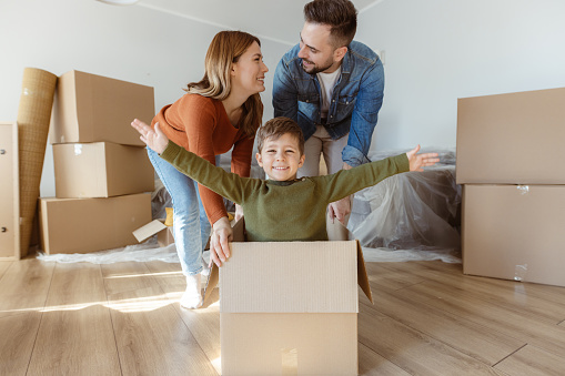 Happy family with one child having fun in their new home surrounded by boxes