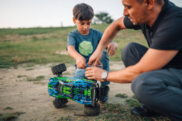 istock Dad and his son fixing toy truck outdoors during play time. 1958337602