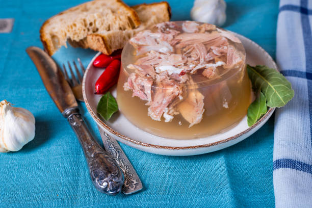 Jelly with meat, beef aspic, traditional dish. portion on plate with homemade bread and chili.