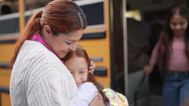 Child girl embracing mother after getting out the school bus