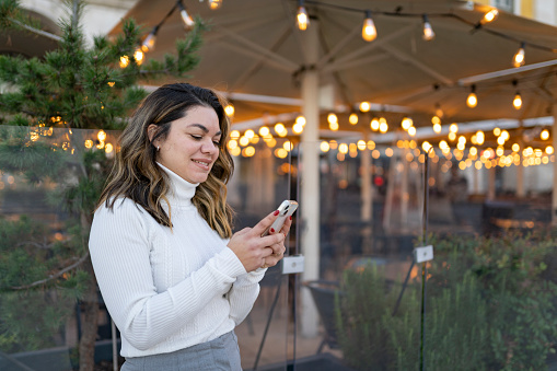 Mature woman using smartphone in front of illuminated terrace