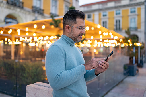 Mature man using smartphone in Praça do Comércio, Lisbon, Portugal
