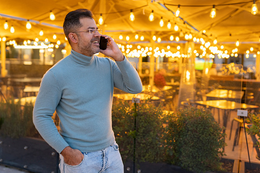 Mature man using smartphone with restaurant backlight