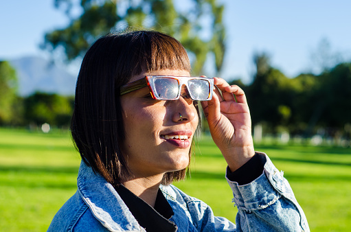 portrait of young woman with bobbed hair dressing casual clothes and sunglasses in public park on a sunny day