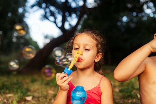 Little girl having fun blowing bubbles in the yard