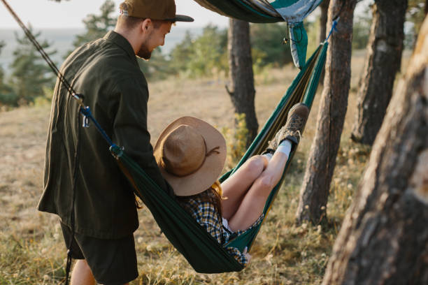 istock A young man helps his girlfriend sit in a hammock. 1958453901