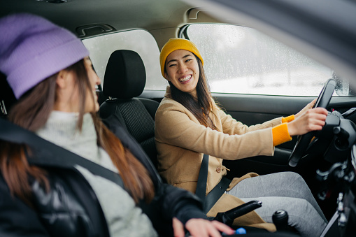 Two young women having a car trip on a snowy day
