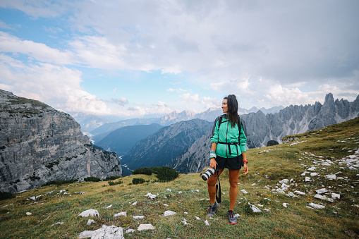 female photographer in the Italian Alps, Dolomites, traveling and capturing the beautiful nature, trees and mountains with her mirrorless or DSLR camera.
