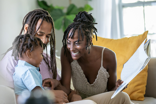 Parents read picture book to young toddler boy