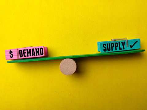 Wooden stick with the word DEMAND SUPPLY on a yellow background