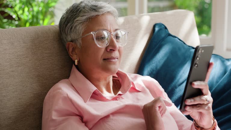 Relax, phone or senior woman on social media with internet connection or website notification on sofa. Glasses, happy or elderly person texting on networking mobile app chat or reading news in home