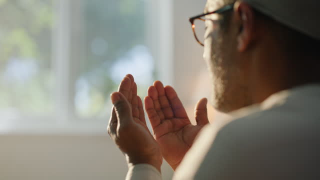 Man, muslim prayer and hands in home for faith, peace or calm for worship, praise or gratitude. Islamic person, living room or dua with back for spiritual guide, religion or hope in apartment in Doha