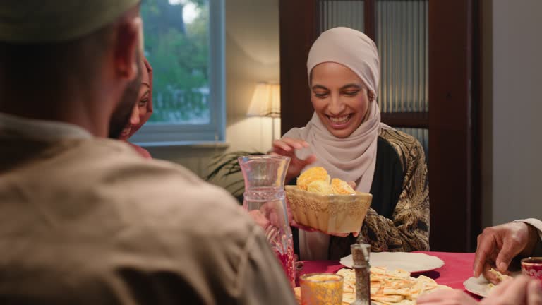 Happy family, muslim or ramadan for sharing meal, laugh or  love of religion by table in home. Islamic festival, tradition and iftar for halal cuisine together in apartment, fasting or celebration