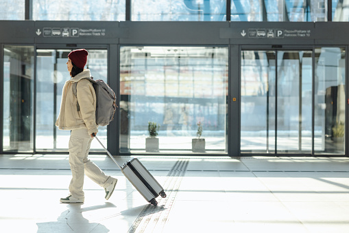 Photo of a smiling Chinese woman with a backpack and suitcase traveling solo