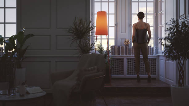 istock Woman in apartment looking through the window 1958743824