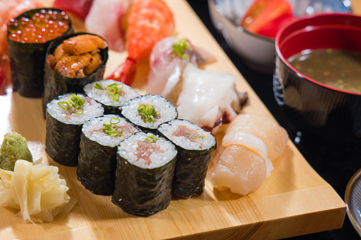 Sushi roll set on a wooden plate with soy sauce and wasabi