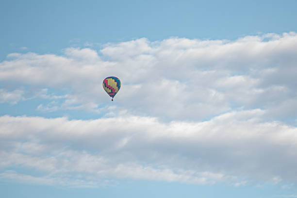 A yellow, red, and blue hot air balloon pictured against a cloudy blue sky.