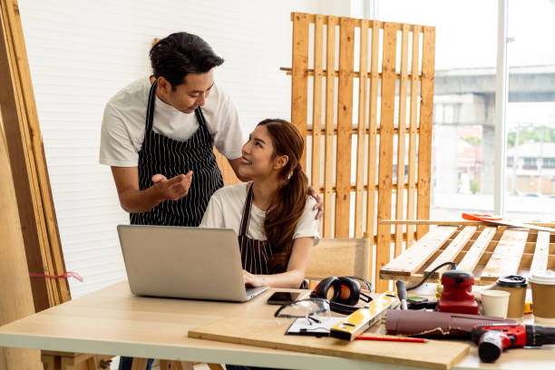 istock Young couple brainstorming creative interior design ideas for their new cafe business start-up on a laptop, choosing flexible workspace layout to drive customer engagement 1958865372