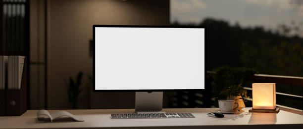 istock A modern dark private office at night with a computer, a table lamp, and accessories on a table. 1958867367